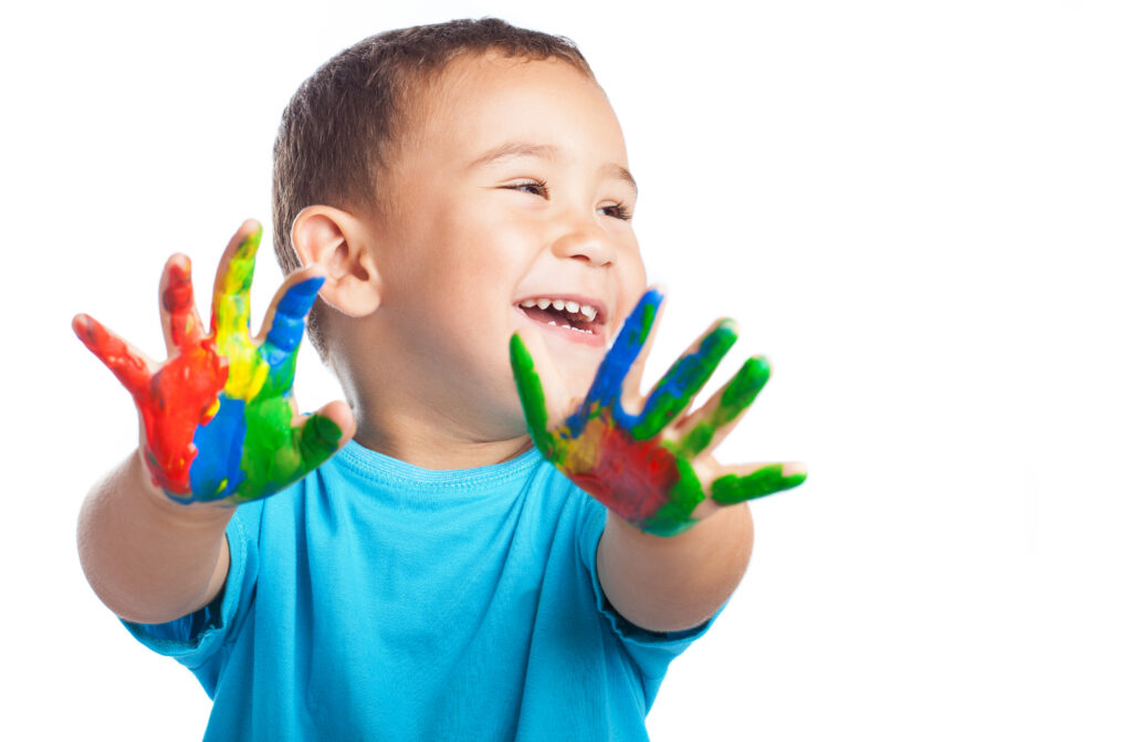 child-smiling-with-hands-full-paint-1024x671 Sinais Precoces do Autismo: Como Identificar nos Primeiros Anos de Vida
