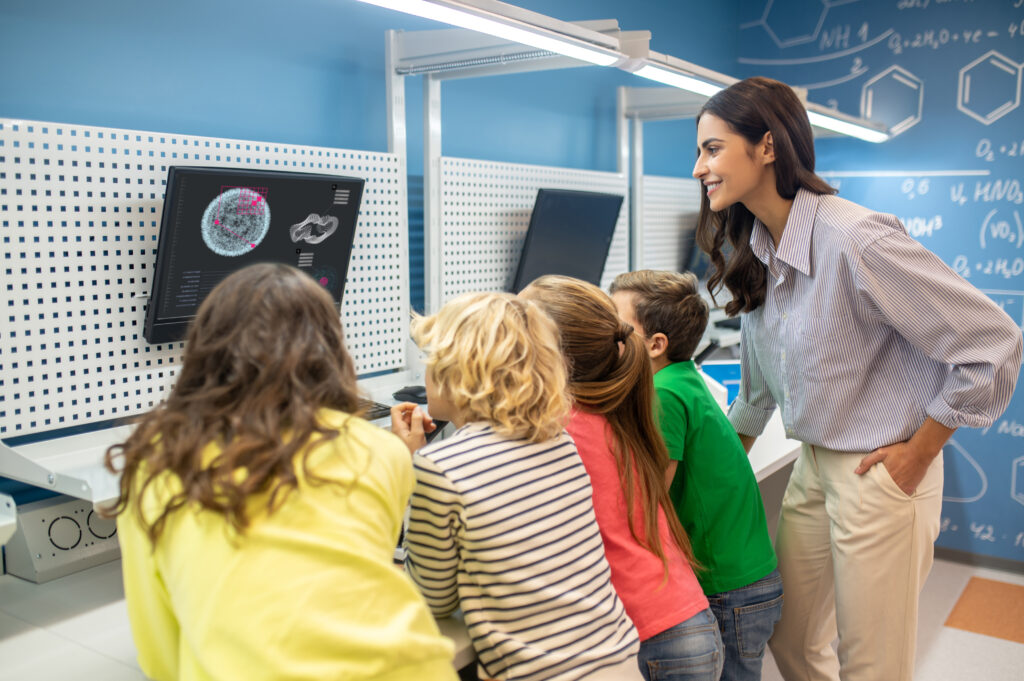 teacher-with-children-looking-screen-lesson-1024x681 Funções Executivas e Desempenho Escolar: Como o Cérebro Impacta a Aprendizagem Infantil
