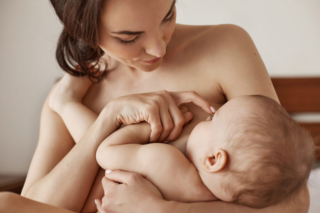 young-tender-nude-mother-breastfeeding-hugging-her-newborn-baby-sitting-in-bed-at-morning-scaled-1-1024x683 A Importância do Vínculo Mãe-Bebê no Desenvolvimento Psíquico